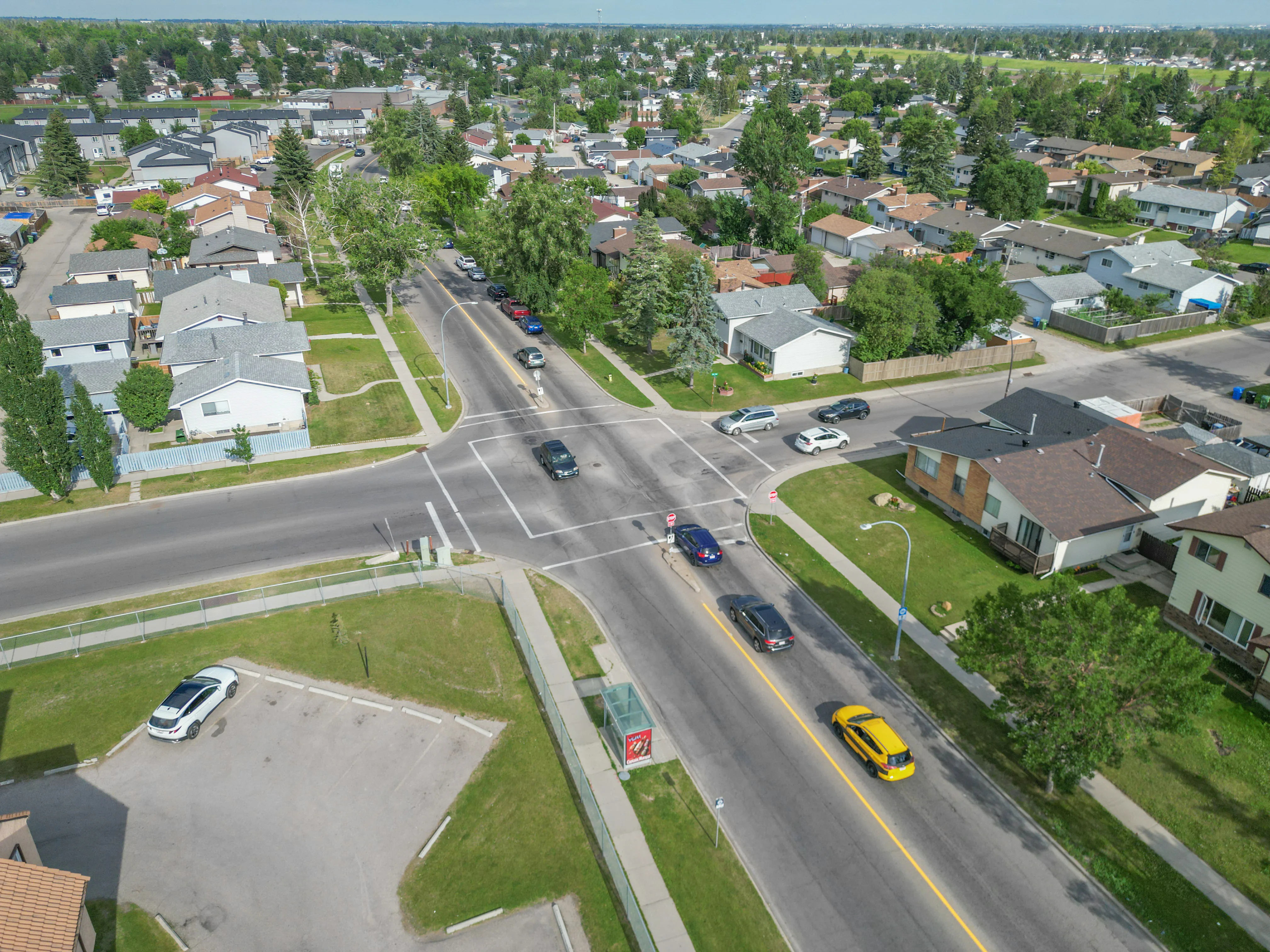 Aerial of homes beside a wide grassy boulevard and a road