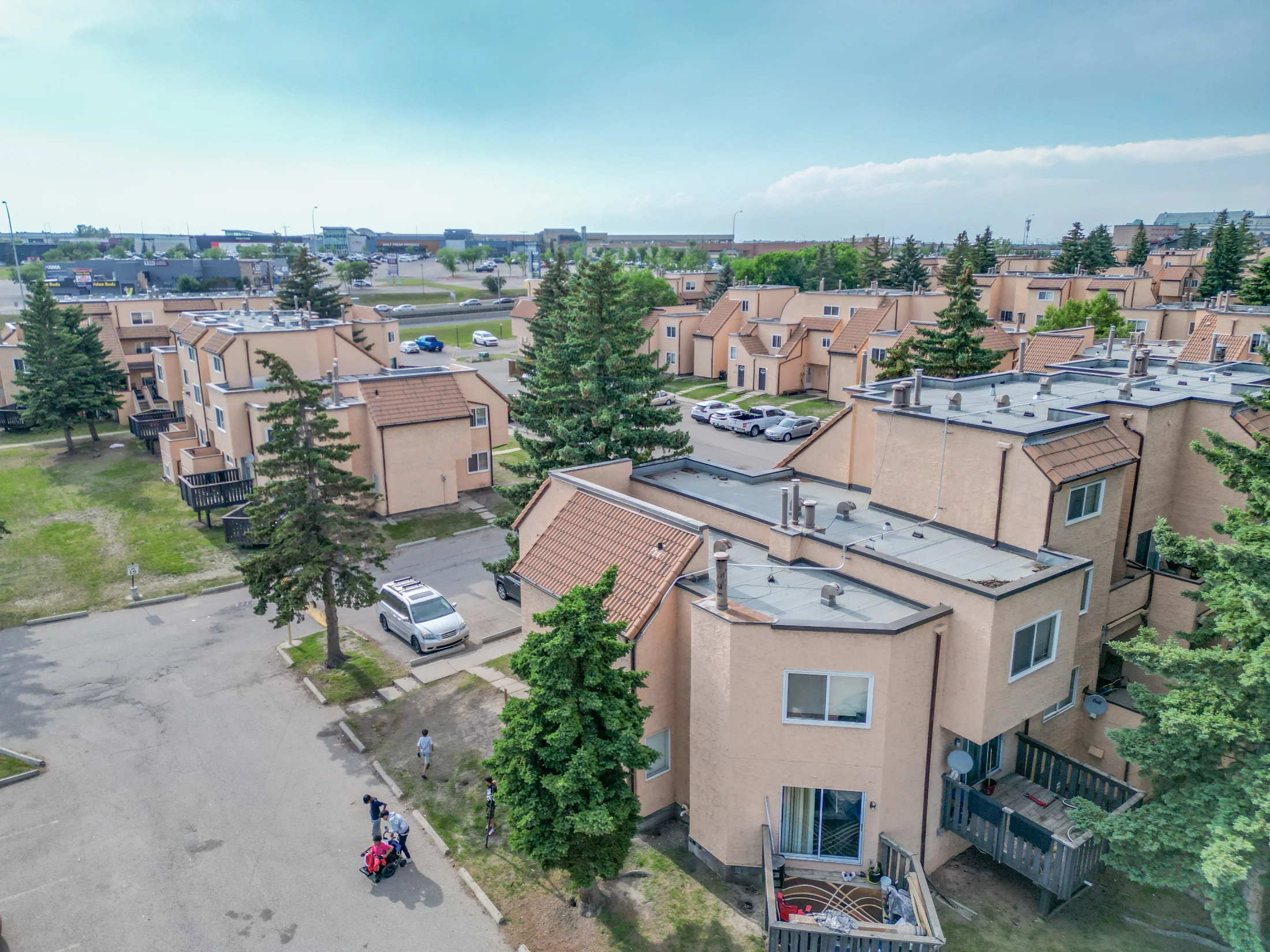 Aerial of townhome rows with pitched roofs among mature trees