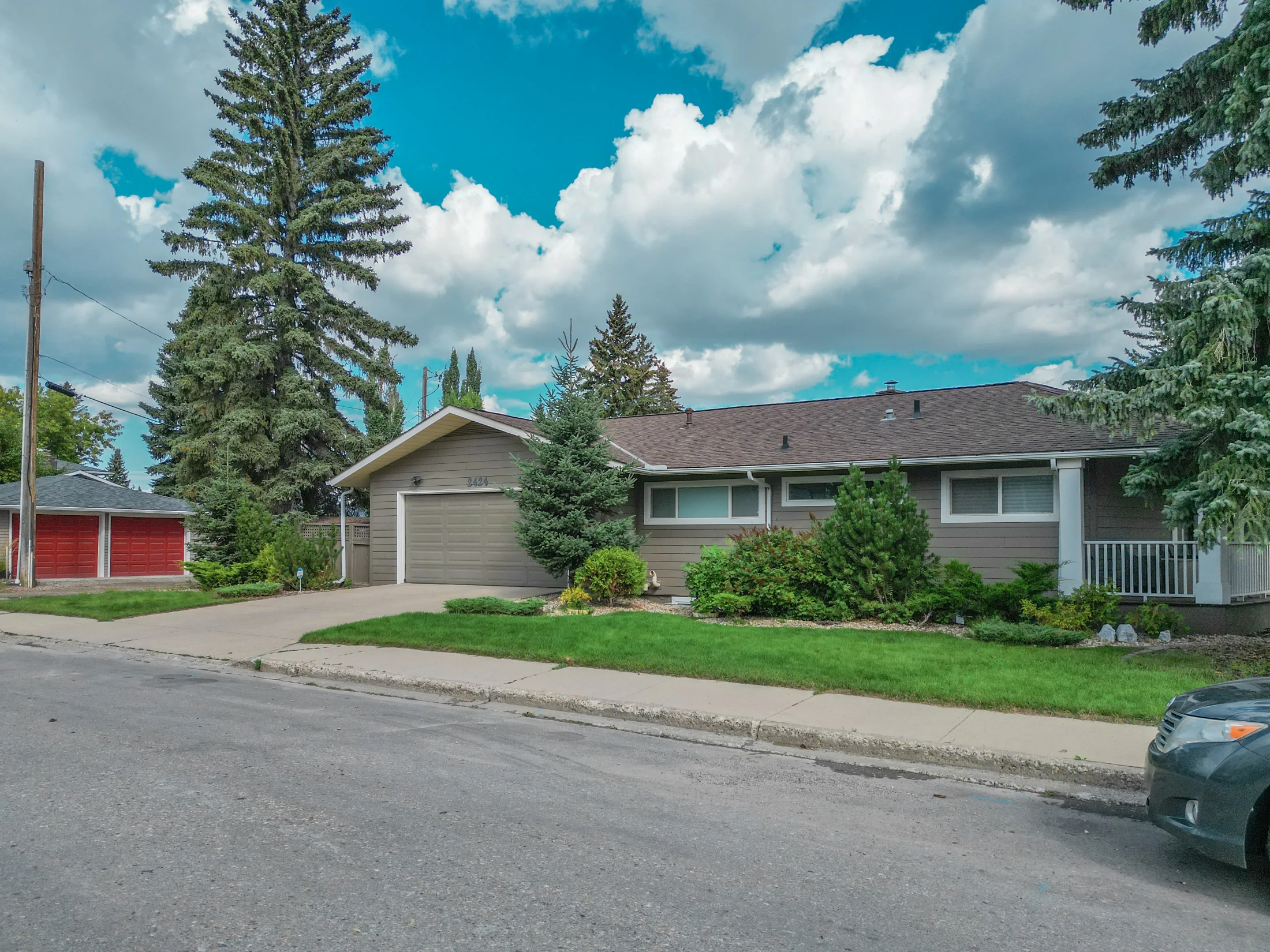 Bungalow with a wide lawn and mature evergreens on a quiet street