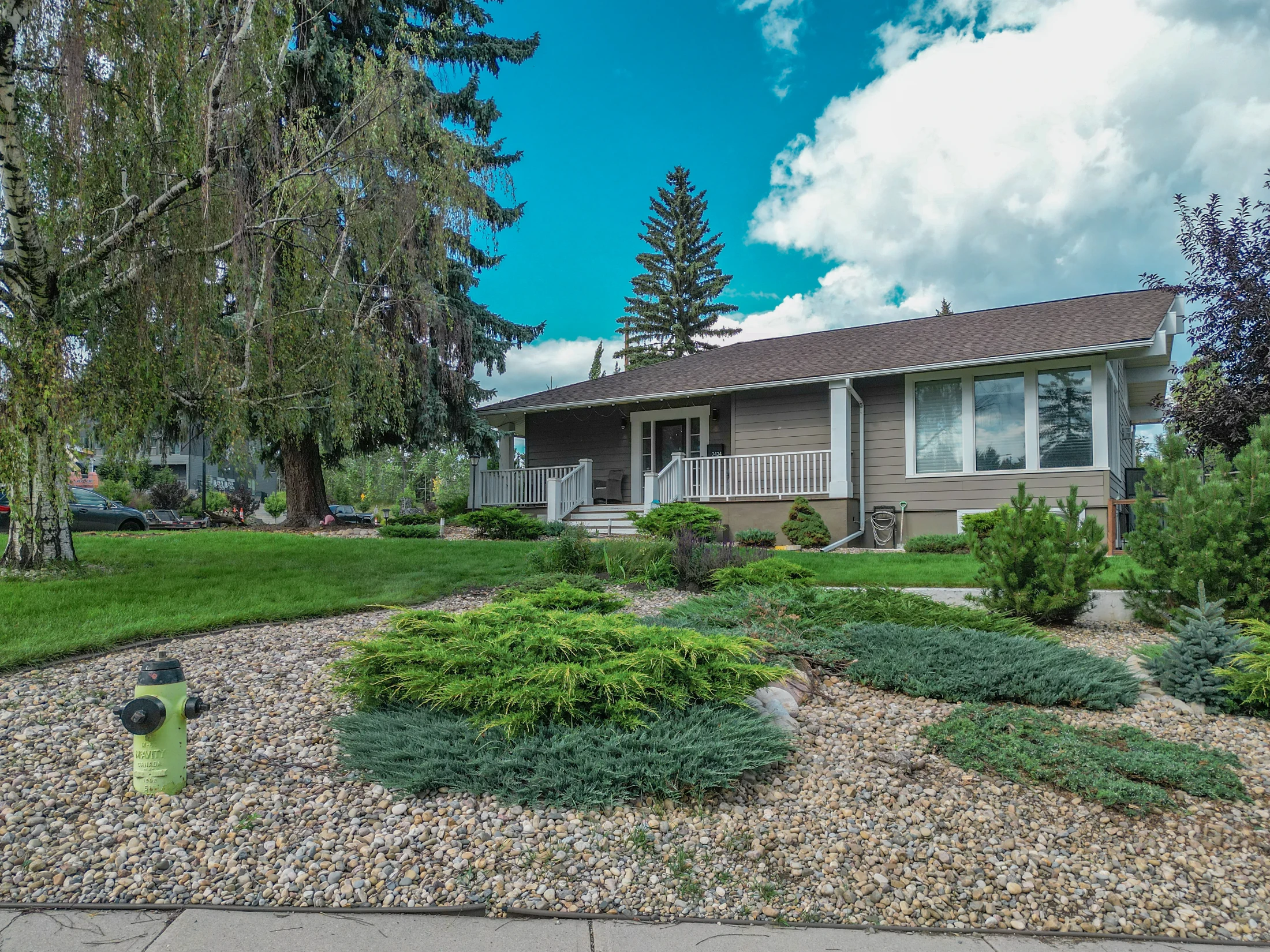 Bungalow on a large landscaped lot with tall spruce trees