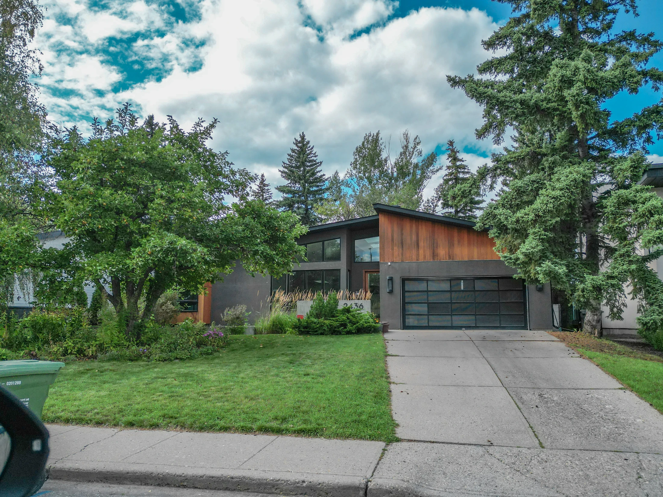 Older home with mature trees and a front lawn on a residential street