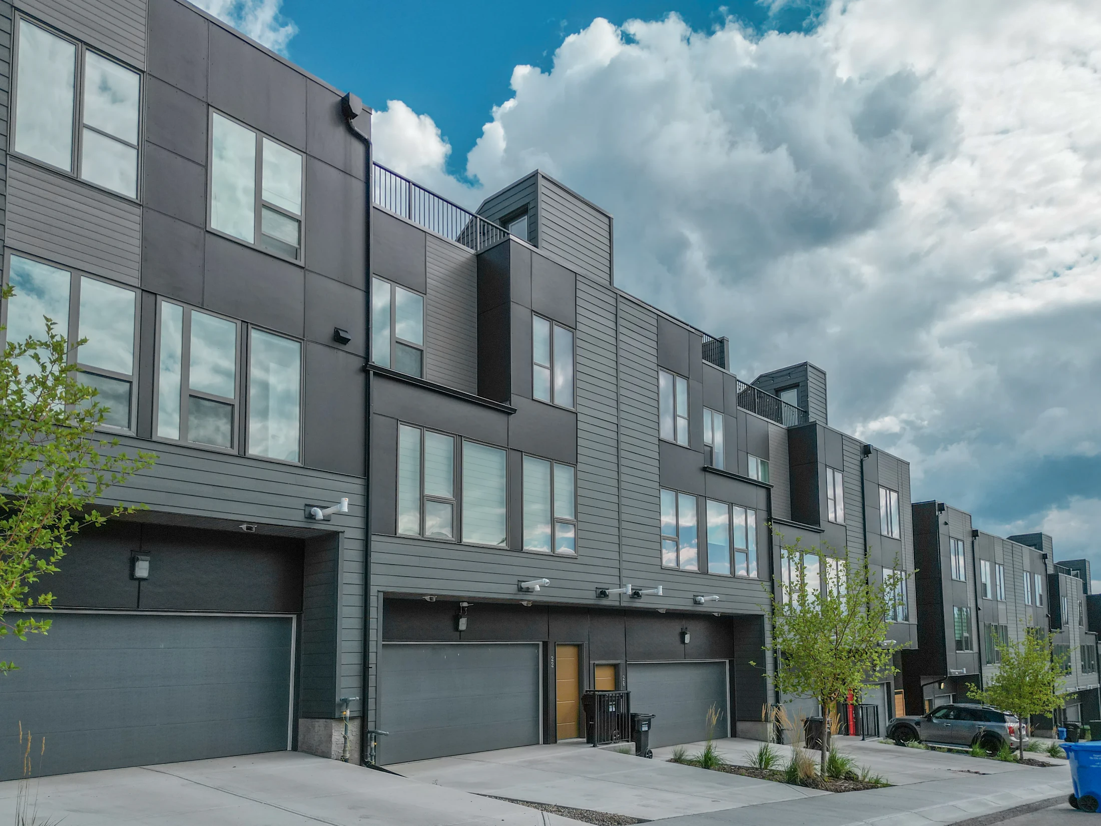 Modern three-storey townhomes with dark siding and garages