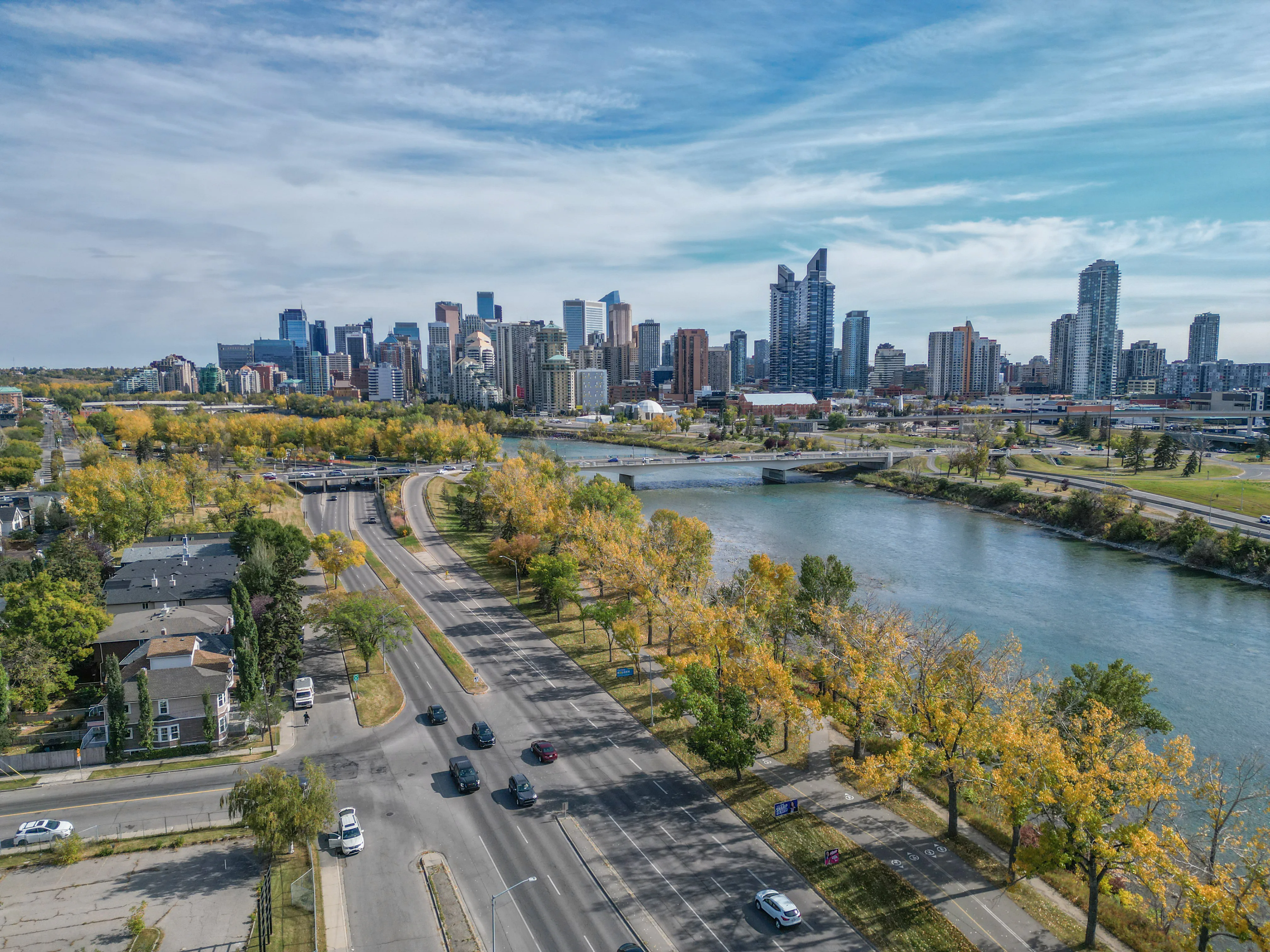 Aerial of a river valley with autumn trees and the city skyline