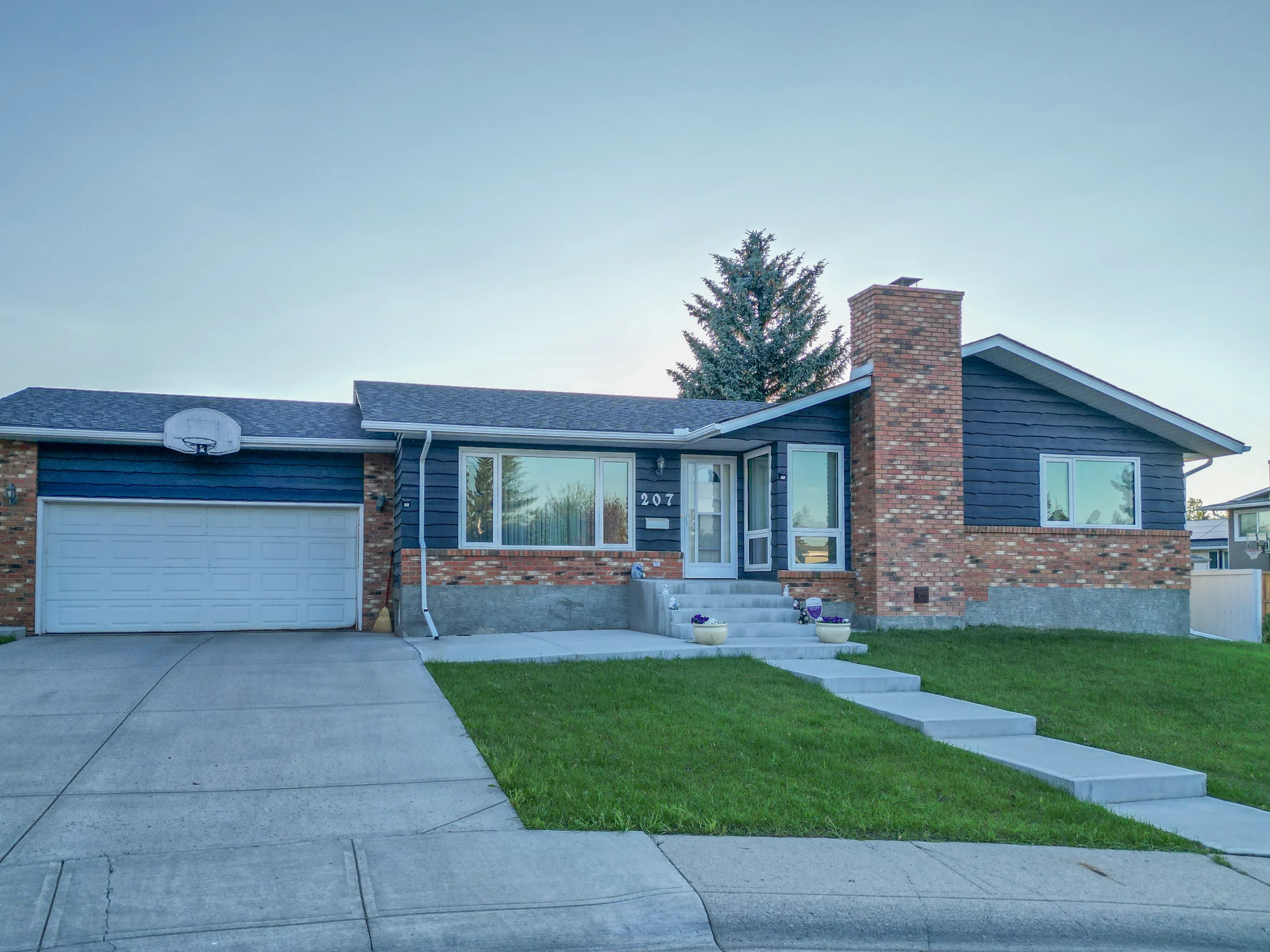 Bungalow with a large front lawn and an attached garage